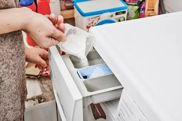 A woman pours detergent into the washing machine