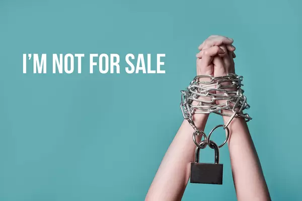 A woman rising her chained hands with text - I am not for sale