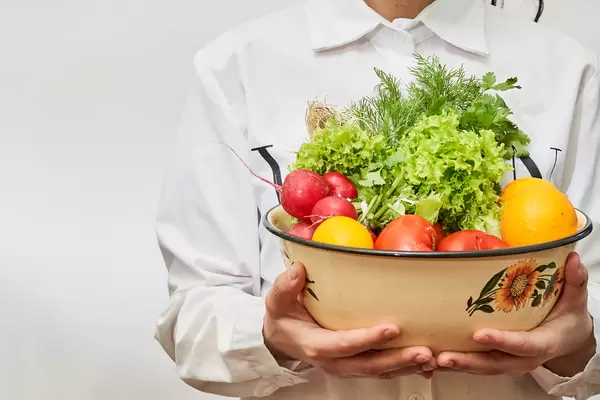 A woman with a bowl full of fresh vegetables