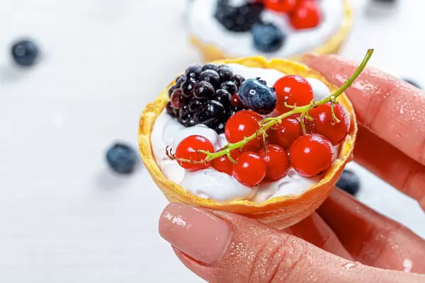 A woman's hand holding a cake with berries and cream. Close up (Flip 2019)