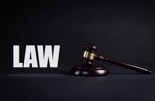 A wooden judge gavel with Law text on black background