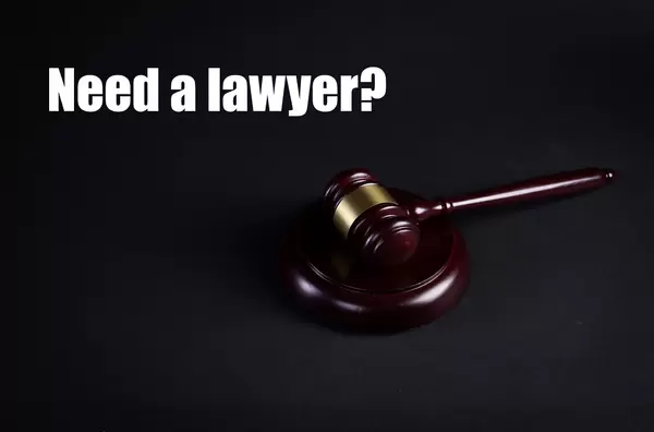 A wooden judge gavel with Need a lawyer text on black background