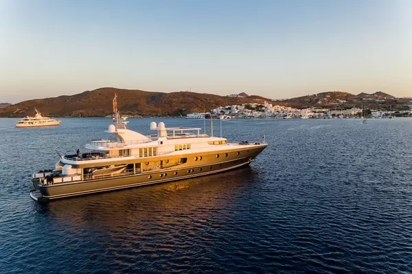 A yacht in calm waters off the coast of Milos, Greece. The town of Adámas in the background