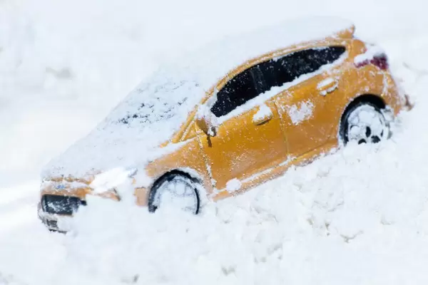 A yellow family car is standing on a snowy road