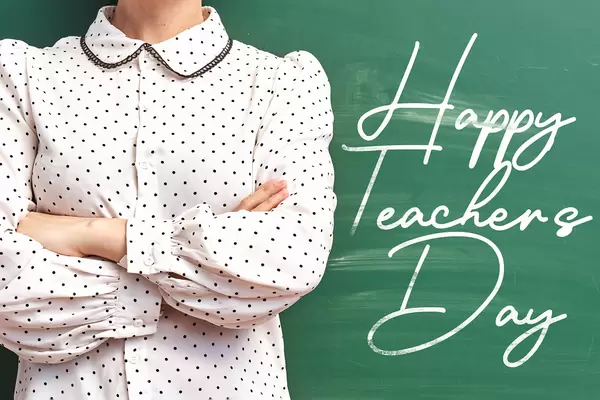 A young teacher posing over chalkboard - Happy teachers day concept