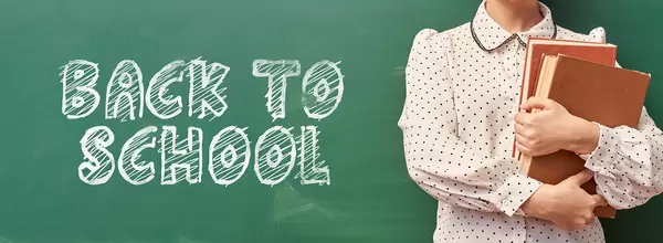 A young teacher with books over classroom chalkboard