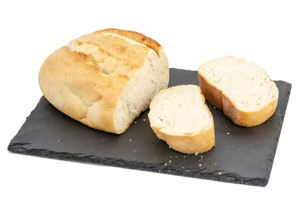 Abgeschnittenes Weißbrot mit zwei Brotscheiben auf einer Schiefersteinplatte