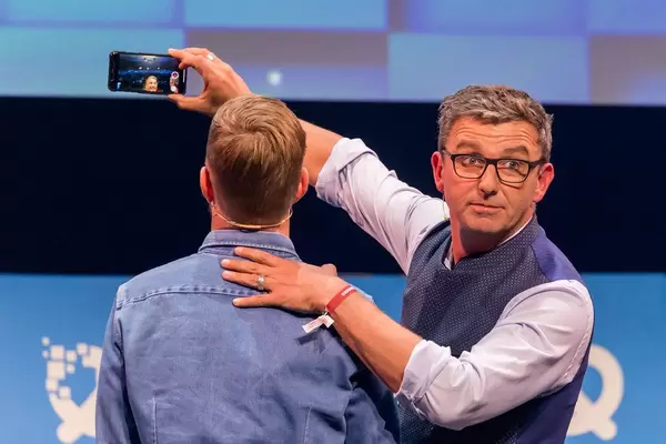 Actor Hans Sigl makes a video with his phone together with Joko Winterscheidt on the Center Stage of the founders' conference Bits19 in Munich