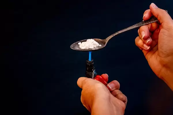 Addiction and drugs. Preparing drugs with a spoon and lighter