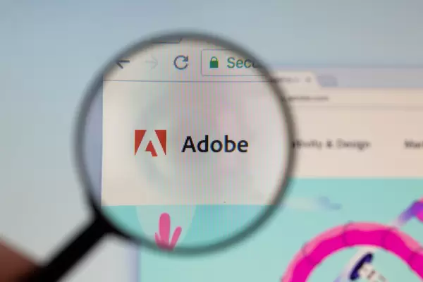 Adobe-Logo am PC-Monitor, durch eine Lupe fotografiert