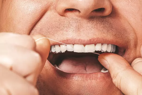 Adult man cleaning flossing his white teeth with dental floss (Flip 2019)