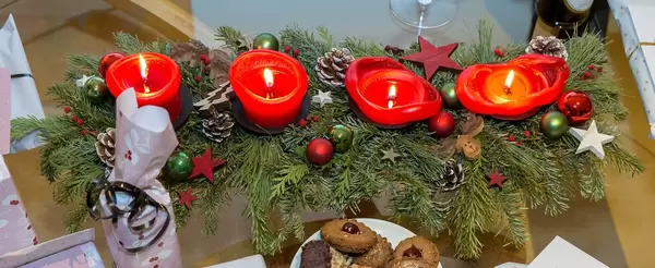 Adventskranz mit vier angezündeten Kerzen sowie Geschenke und Weihnachtskekse