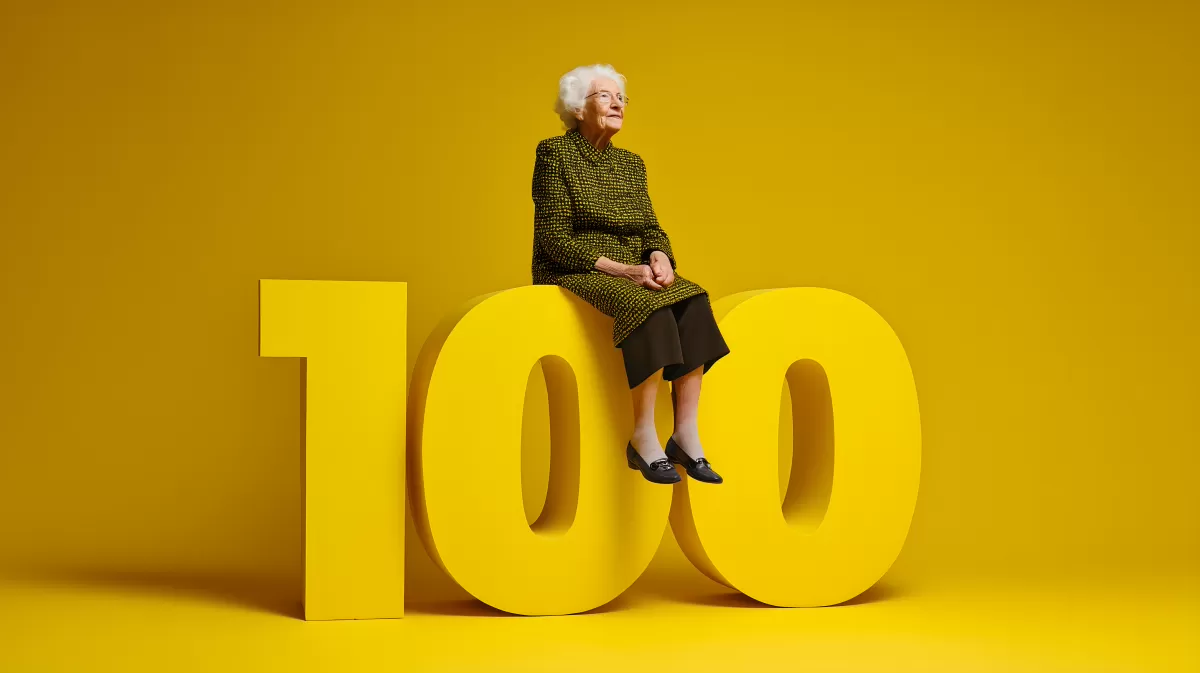 Ältere Dame sitzt stolz auf großer Zahl 100