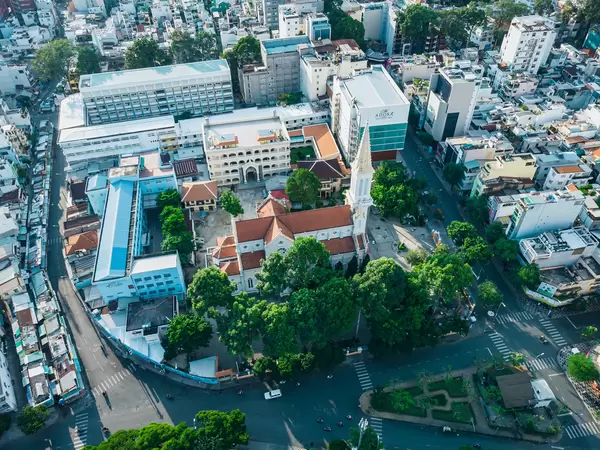 Aerial Drone Photo of  Catholic Huynh Si Church with many Trees and Buildings around it in the City Center of Ho Chi Minh City, Vietnam