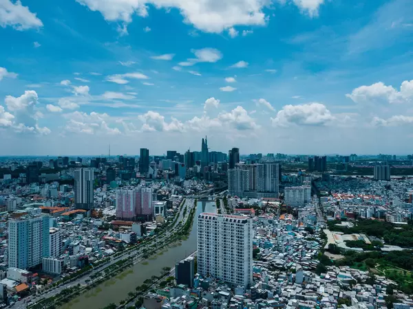 Aerial Drone Photo of Ho Chi Minh City, Vietnam with many Apartment Buildings, Bitexco Financial Tower in District 1, Saigon River, Landmark 81 on a Cloudy Day