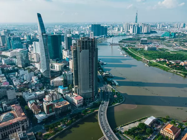 Aerial Drone Photo of the City Center in District 1 with Bitexco Financial Tower with Heli Pad, Bridge Construction over Saigon River and Landmark 81 Tower in the Background in Ho Chi Minh City, Vietnam