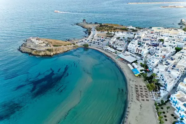 Aerial photo of the Agios Georgios beach, the blue waters and the blue-white buildings of Naxos City