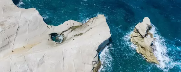 Aerial photo of the white cliffs of Sarakiniko in Milos, with a hole shaped by the waves
