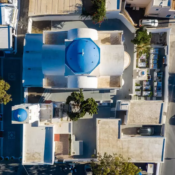Aerial photo of typical Greek church and bell tower with blue domes and small cemetery