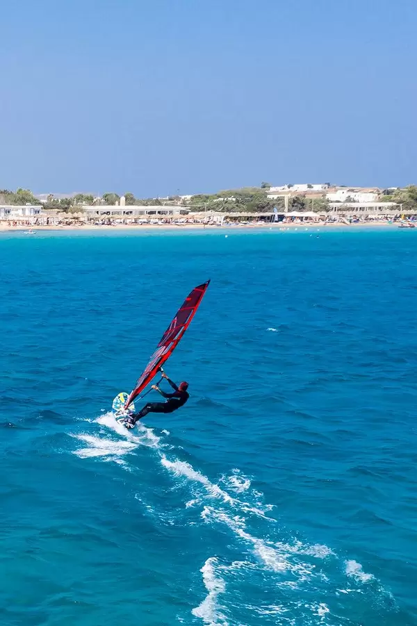 Aerial photography of a fast windsurfing water sports enthusiast in front of Santa Maria Beach of Paros, Greece, in the Mediterranean Sea