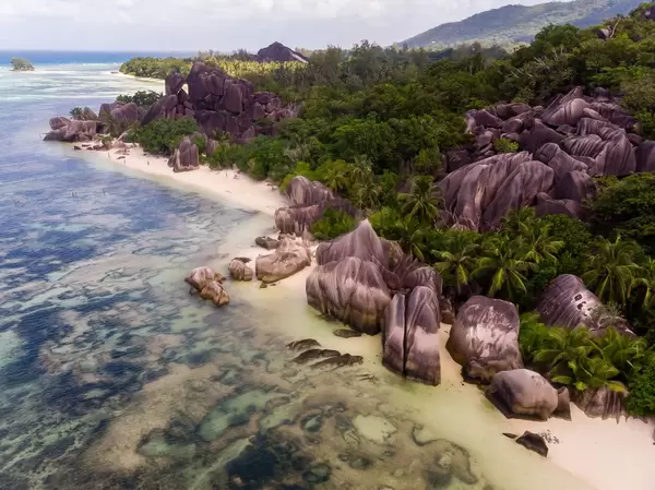 Aerial photography of multicolored granite rocks on Anse Source d'Argent Beach with swimming people in the Indian Ocean, Seychelles