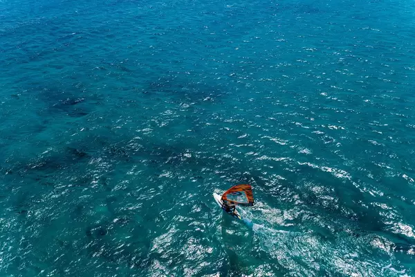 Aerial picture and top view of a man on a surfboard windsurfing on the blue water of the Mediterranean Sea