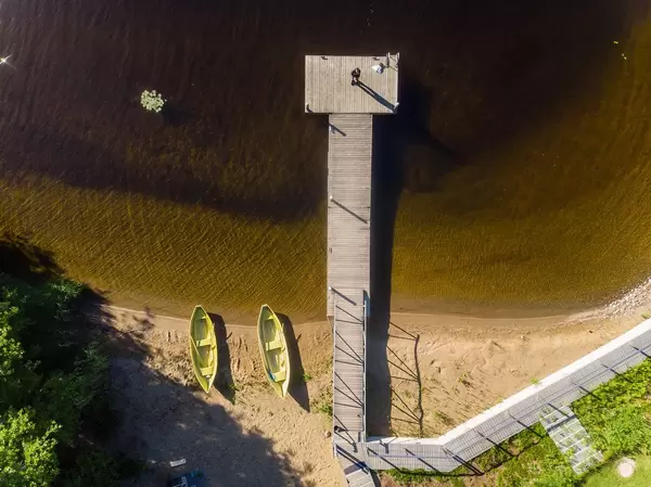 Aerial shot of a wooden jetty in front of luxury guesthouse Villa Jolla, with green rowing boats at the shore of Päijänne-lake, near Tampere, Finland