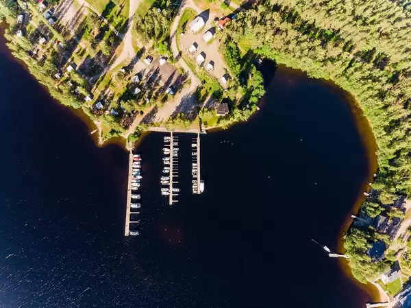 Aerial shot shows yachts and motorboats dock at wooden jetties on Päijänne lake at Padasjoki