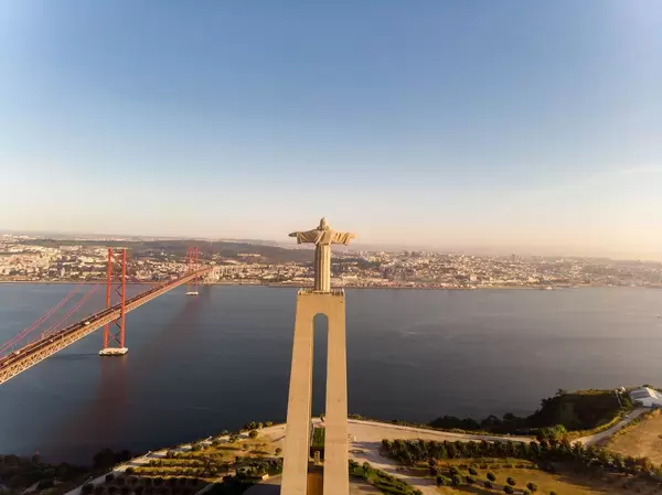 Aerial view from behind of the Cristo rei monument with ponte 25 de abril bridge in Almada Lisbon