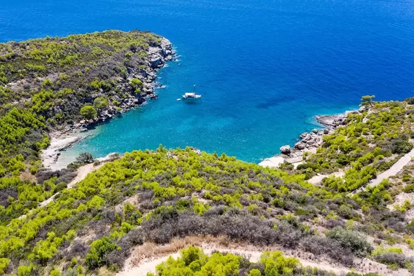 Aerial view from Spetses to a boat in the blue sea at Bekiri's Cave Bay