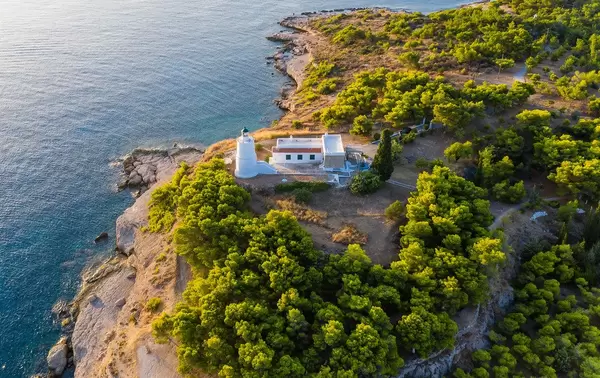 Aerial view of a lighthouse on the remote part of the island Spetses, Greece, next to the rocky coast and the blue ocean