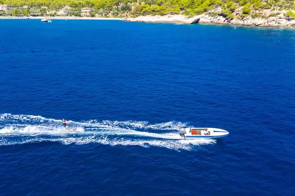 Aerial view of a sports man on waterskis in action, on the blue sea of the Argolic Gulf in front of Agii Anargiri Beach on Spetses, Greek