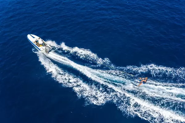 Aerial view of a standing water skier behind a sports boat on the Agogic Gulf