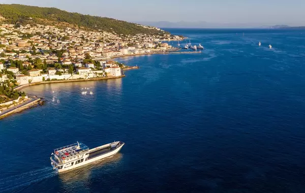 Aerial view of an empty cargo ship on the blue Argolic Gulf in the Aegean Sea, leaving the port of Spetses