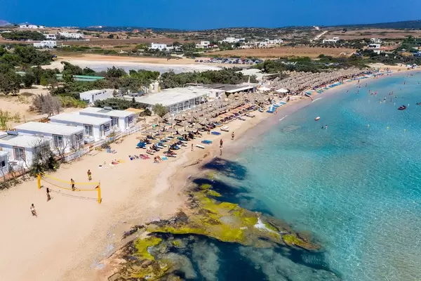 Aerial view of holidaymakers playing beach volleyball and relaxing at Santa Maria Beach, Paros, at the coast of Aegean Sea