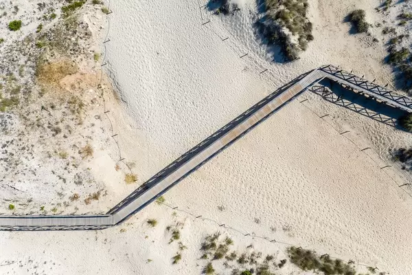 Aerial view of long wooden pathway on the sand across the beach of Cala Mesquida, Mallorca
