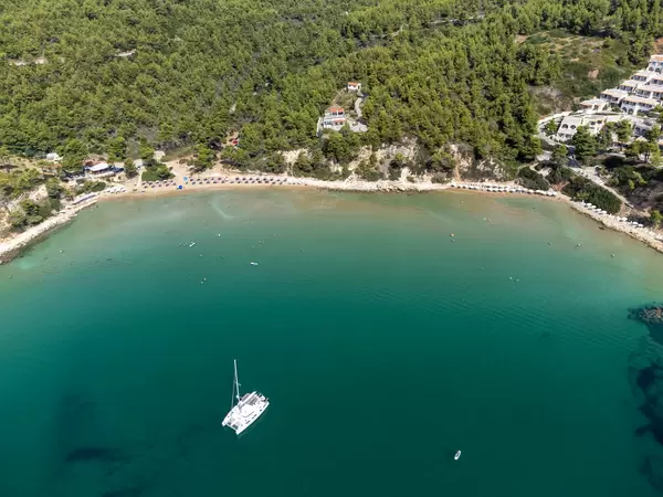 Aerial view of the beach and bay of Chrisi Milia with a catamaran in the turquoise sea