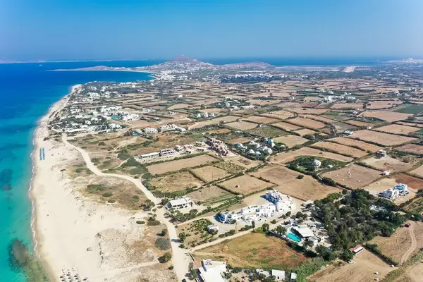Aerial view of the island of Naxos, Greece with flat farmland, beach and stunning transparent waters