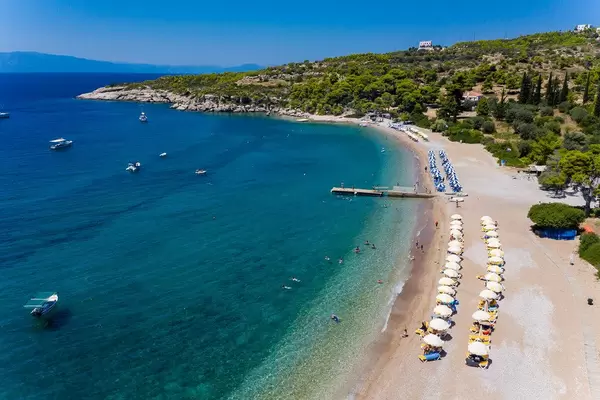 Aerial view of yellow and blue deckchairs in a row, under parasols, on a beach in Agii Anargiri, at the Myrtoan Sea