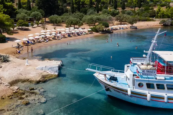 Aerial view shows the anchorage of a ferry at the island Spetses, with tourists swimming in the argolic gulf, in front of the green pine forest