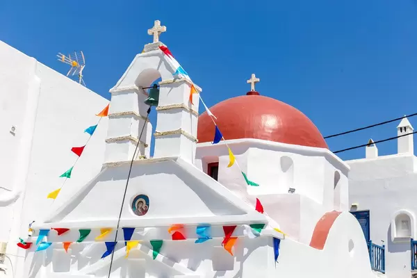 Agia Anna, Mykonos: weiße Kirche mit roter Kuppel und Girlande zum Gedenktag der Heiligen Anna