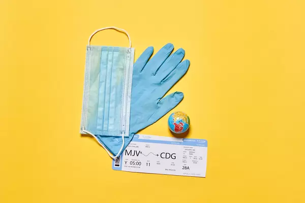 Air ticker, face mask, medical glove and miniature globe - as a symbol of new normal in the travel industry