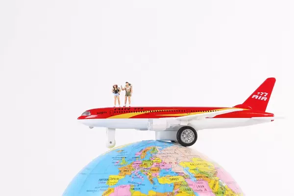 Airplane with miniature travelers on globe