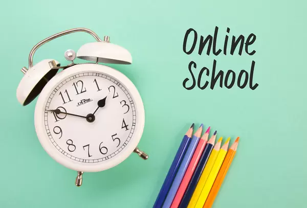 Alarm clock and colored pencils with Online School text