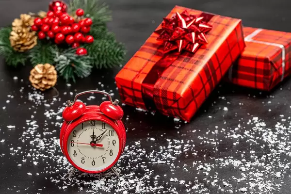 Alarm clock and red decorated gift boxes on a black background with snow and Christmas tree branches (Flip 2019)