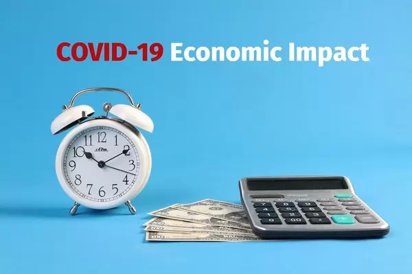 Alarm clock, calculator and money with COVID-19 Economic Impact text