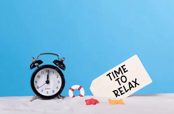 Alarm clock on the beach with Time to relax sign