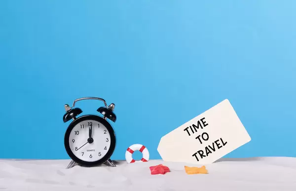 Alarm clock on the beach with Time to travel sign