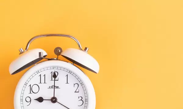 Alarm clock on yellow background with empty space