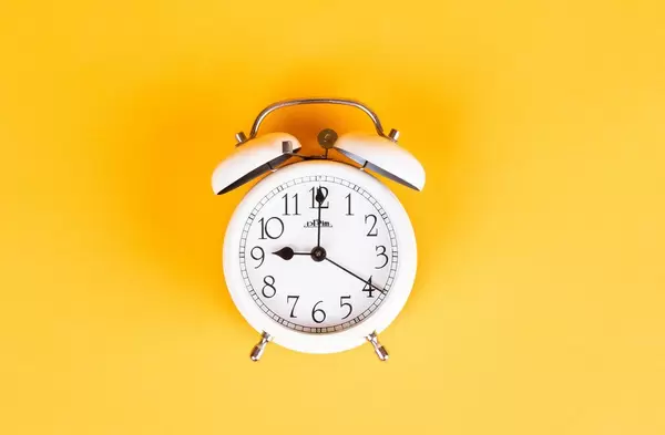 Alarm clock on yellow background